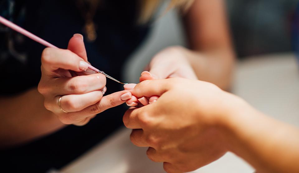 nail technician holding a clients hand giving a manicure one salon nail services